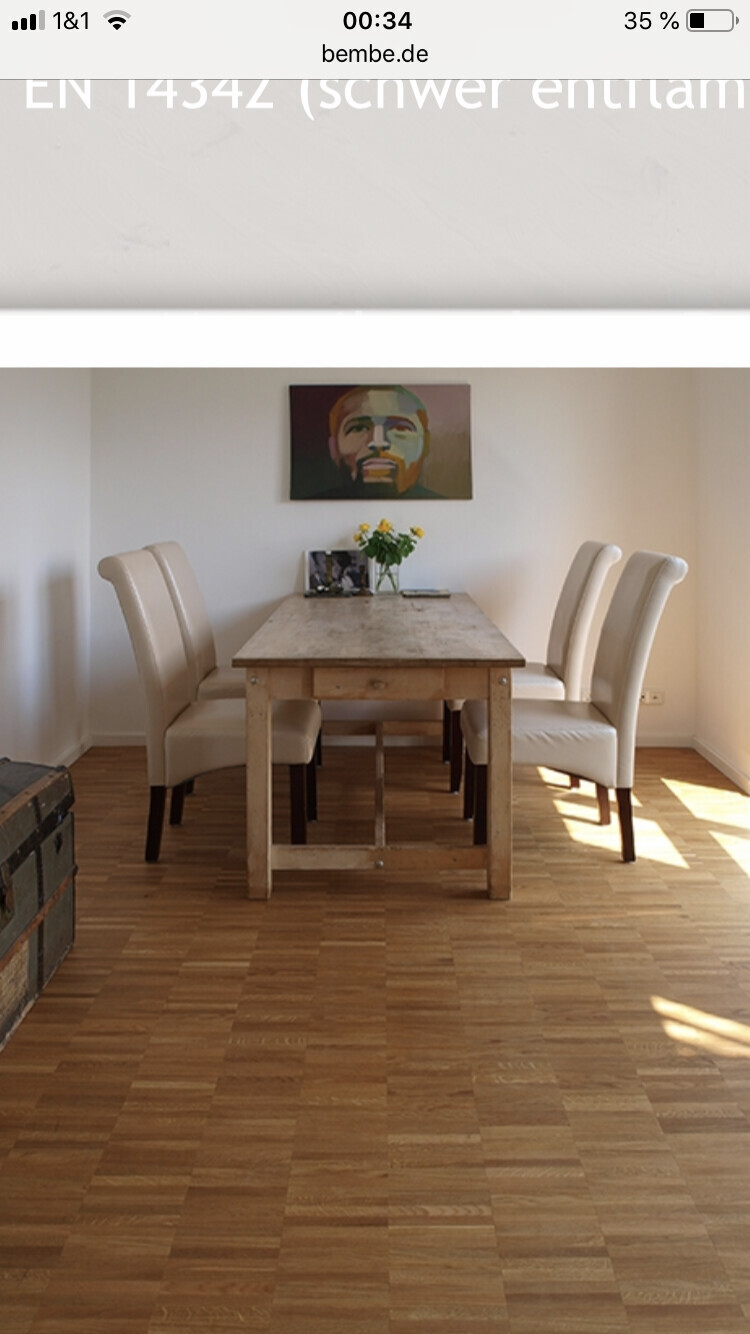 Helles Esszimmer mit rustikalem Holztisch, gepolsterten Stühlen und Wandbild.