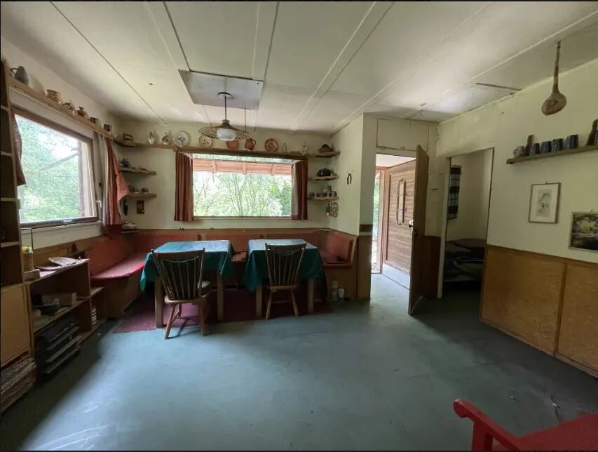 Rustikales Esszimmer in einer Hütte: Esstisch mit grünem Tischtuch, Bänke, Regale, Fensterblick