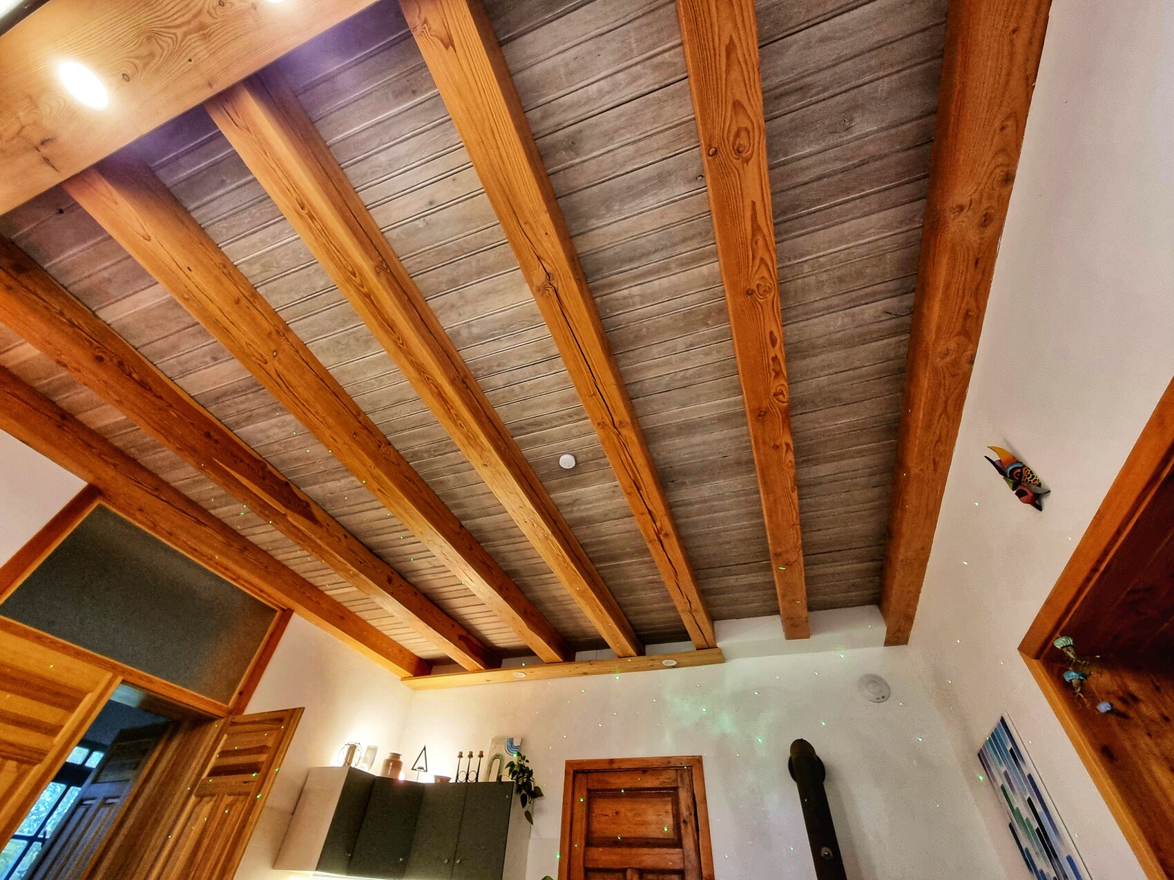 Wohnzimmer mit sichtbaren Holz-Deckenbalken, Kaminofen und moderner Einrichtung