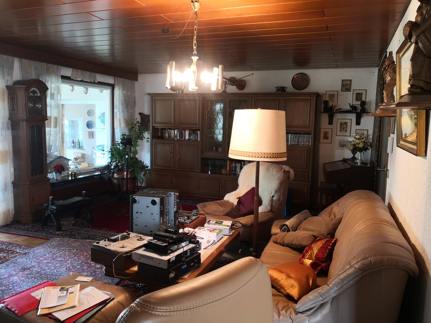 Gemütliches Wohnzimmer mit Leder-Sofa, Holzmöbeln, Teppich und Technik auf dem Couchtisch.