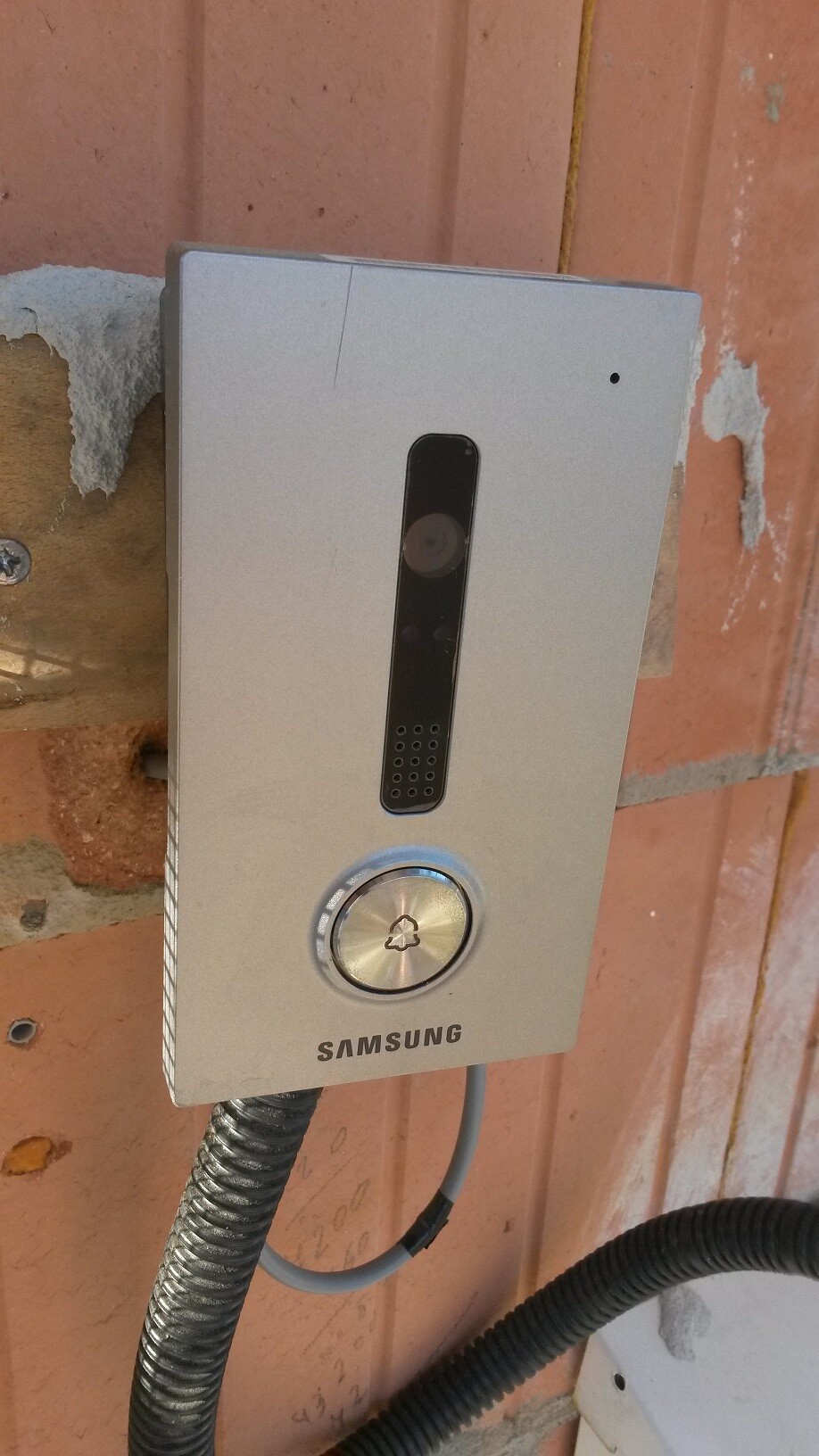 Silbernes Samsung-Türsprechanlage-Gehäuse mit Kamera, Klingelknopf und Lautsprecher an Backsteinwand