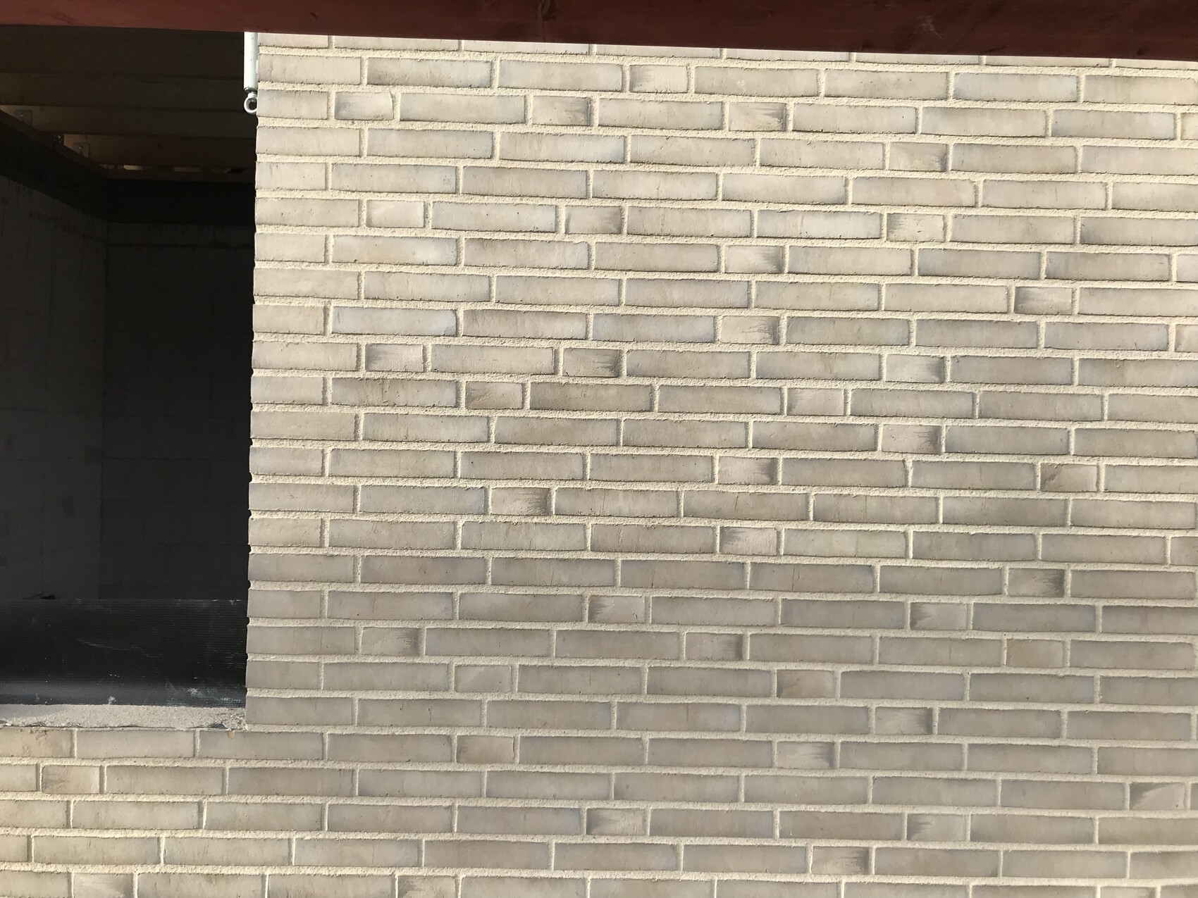 Sandfarbene Ziegelwand mit offener Tür zum dunklen Innenraum