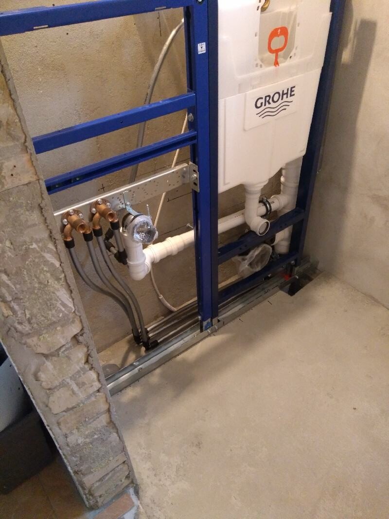 Unterputz-Spülkasten von Grohe in Metallrahmen, sichtbare Rohre und Anschlüsse.
