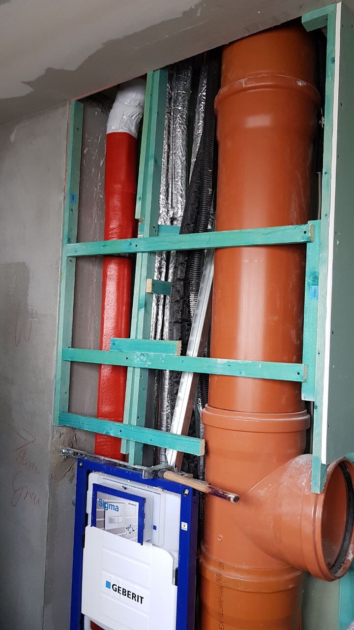 Rohbau-Sanitaerinstallation: gruenes Stenderwerk, oranges Abwasserrohr, Geberit-Modul