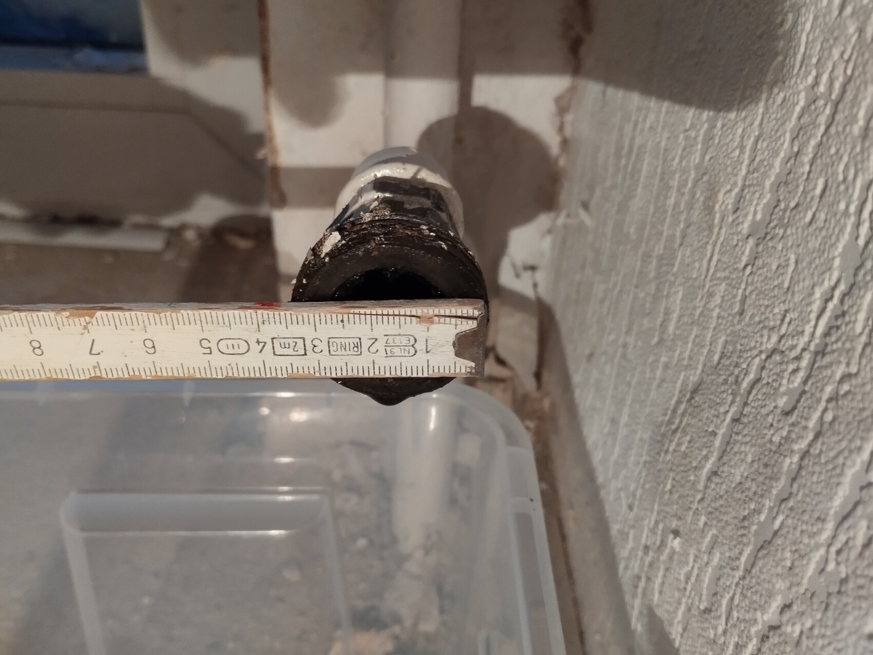 Nahaufnahme eines Rohrs mit Messband, das Lochdurchmesser misst, Wand im Hintergrund