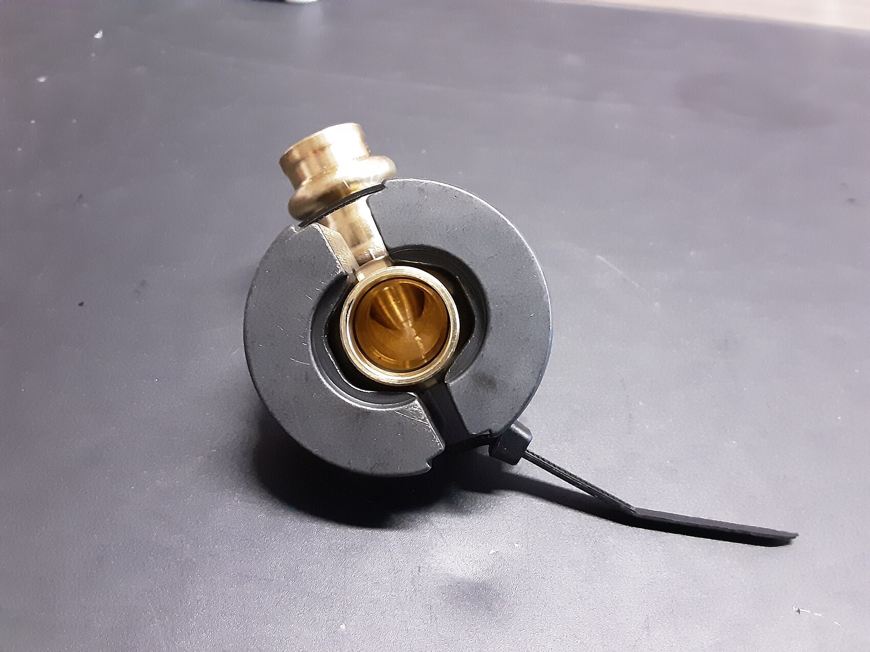 Nahaufnahme eines runden Metallbauteils mit goldenem Innenring und Schraubbolzen.