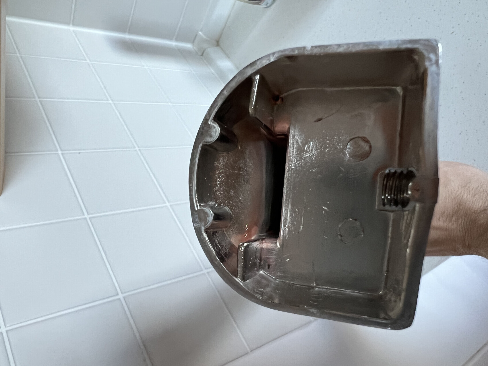 Nahaufnahme eines metallischen Sanitär-Teils mit Gewinde vor Fliesen.