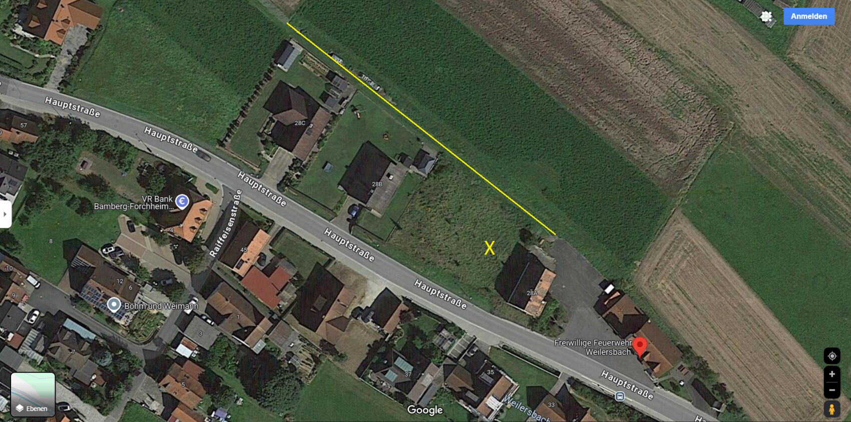 Satellitenbild: Hauptstraße mit gelber Linie über Felder, X-Markierung.