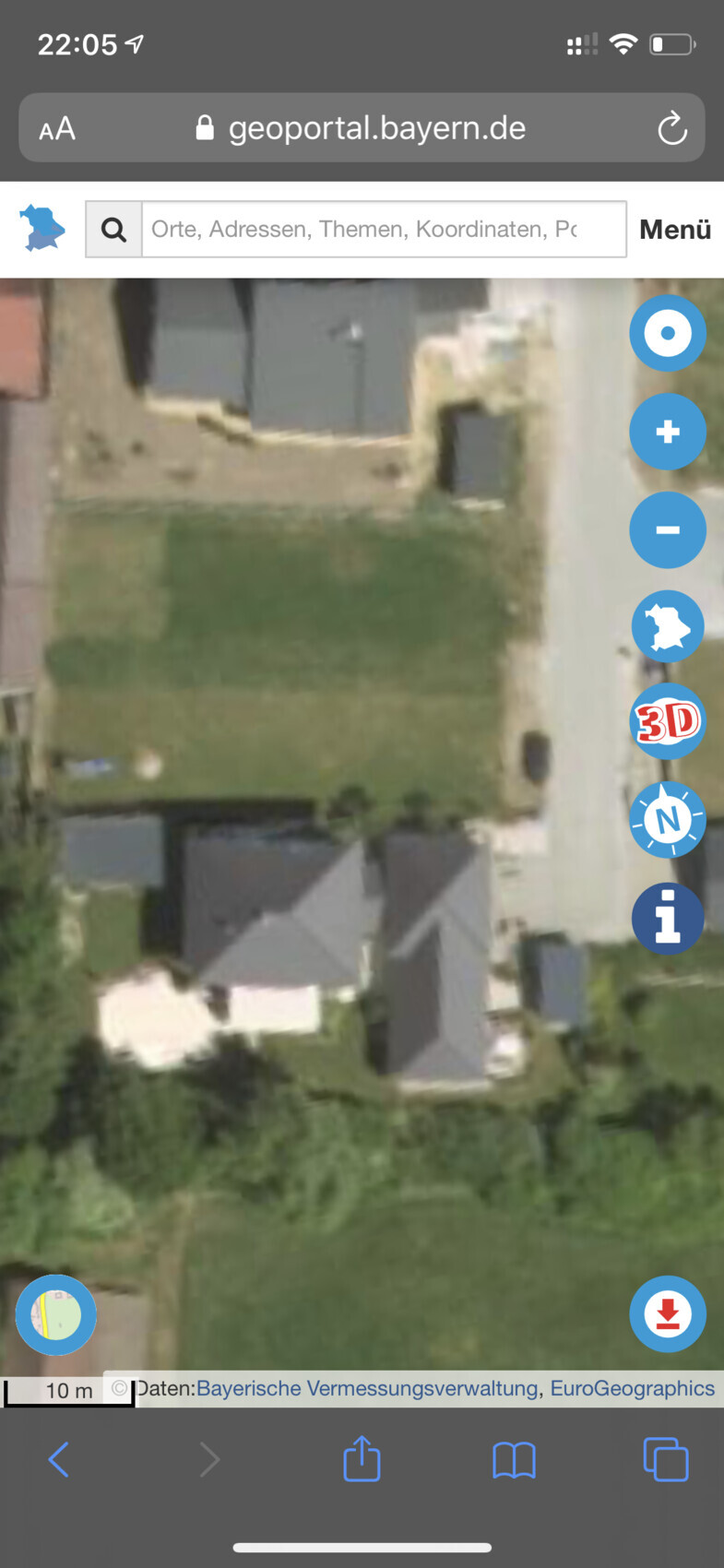Luftbild eines Wohngebiets mit Häusern, Gärten und einer Straße rechts.