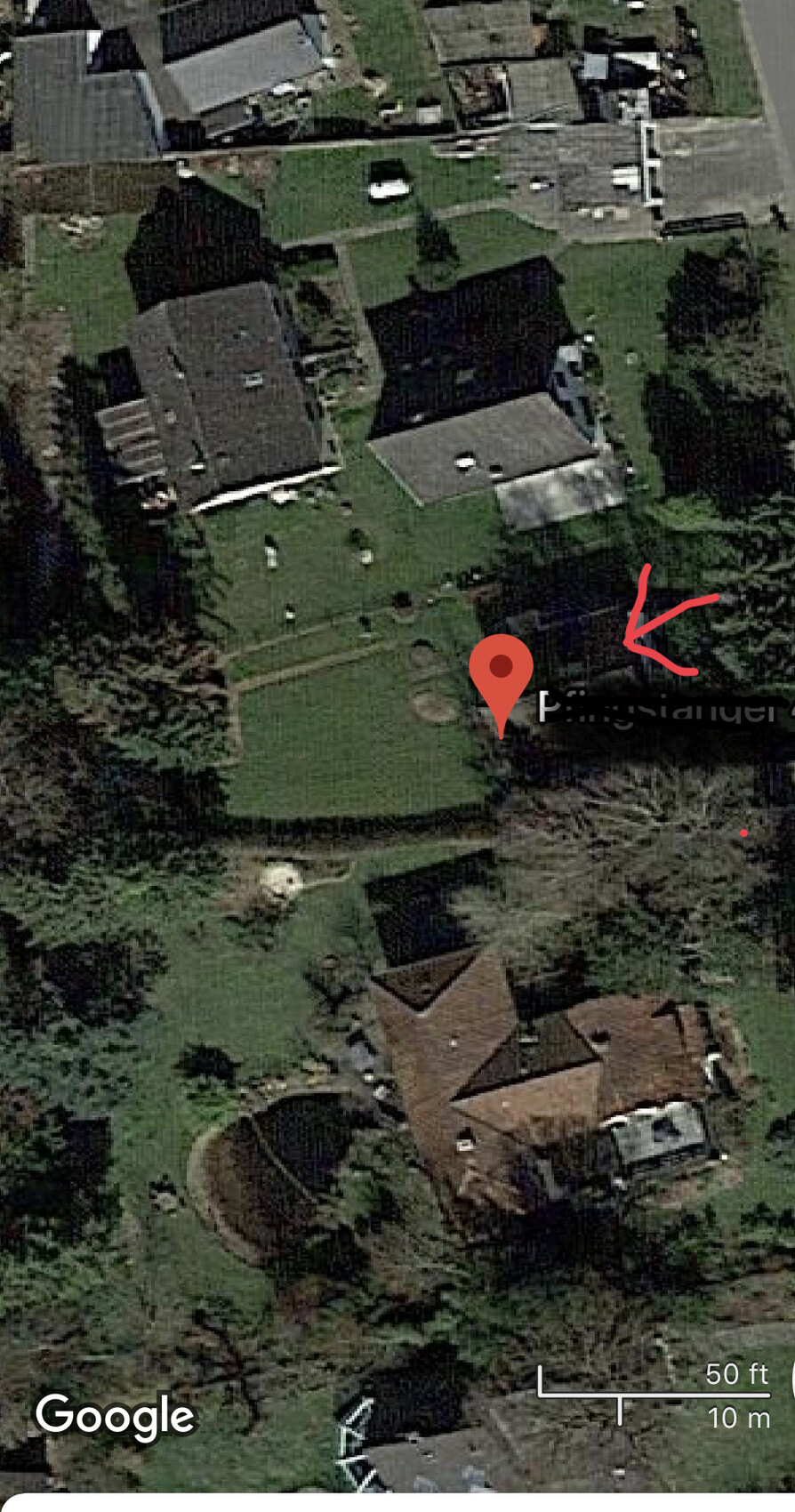 Satellitenaufnahme eines Wohnviertels mit Häusern, Gärten und Standortmarker