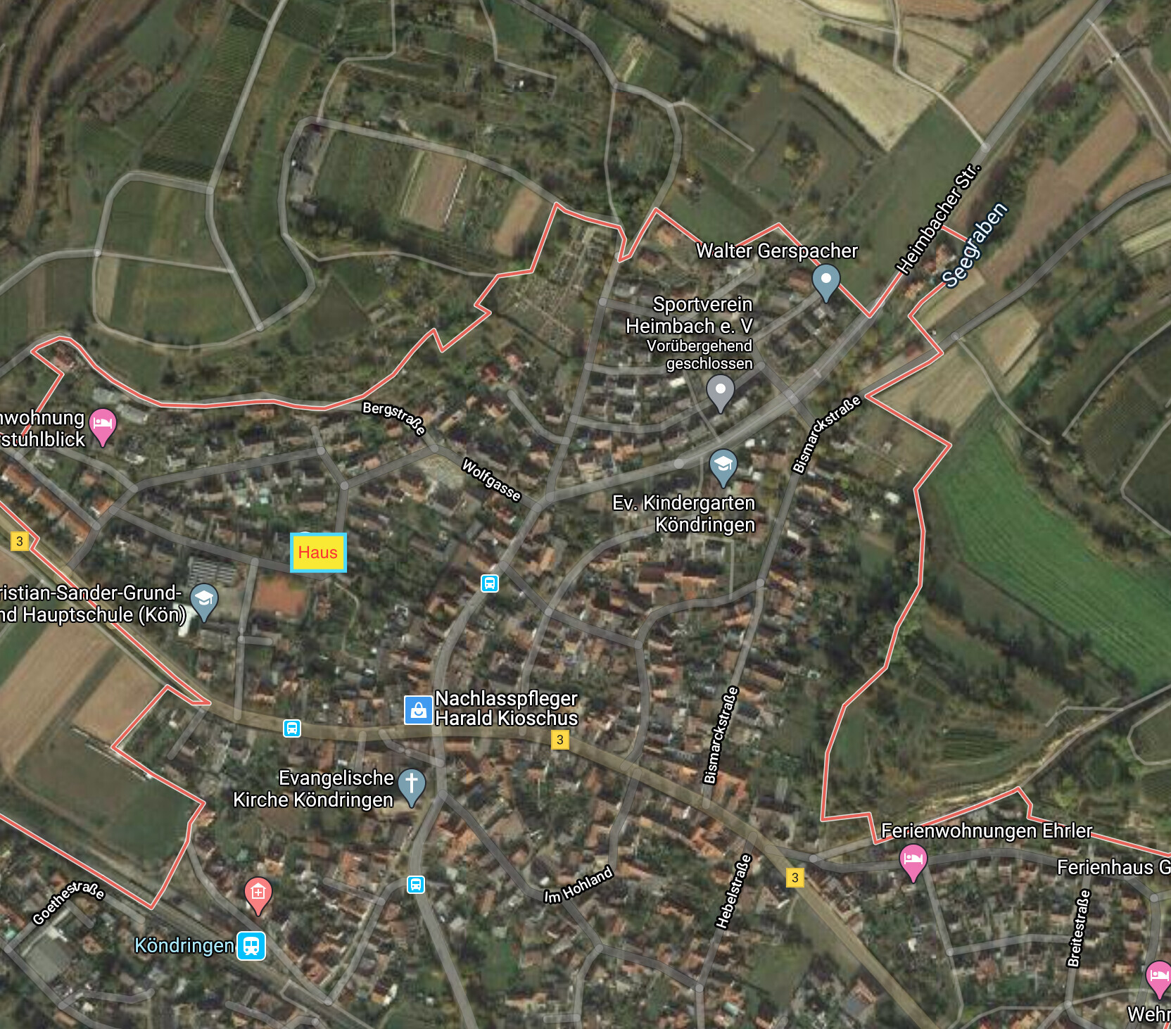 Luftbild von Köndringen mit roter Grenzlinie, gelb markiertes Haus, Straßen und Kirche sichtbar.