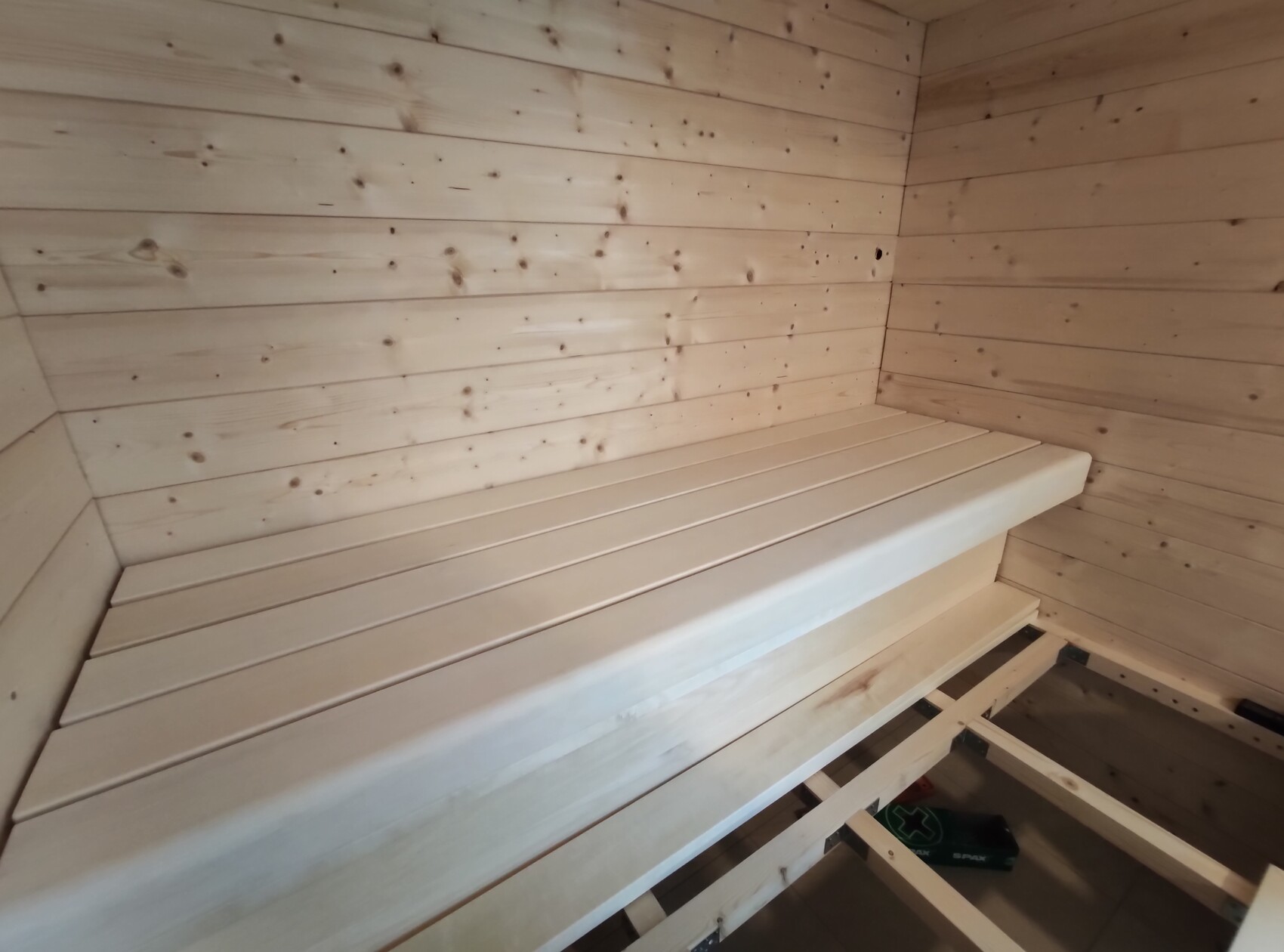 Heller Saunaraum aus Holz mit langer Sitzbank entlang der Wand und Holzverkleidung.