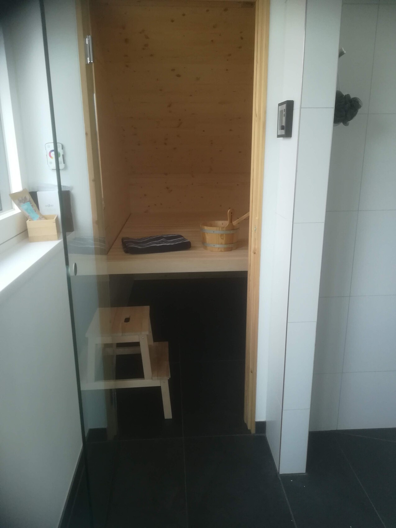 Kleine Holzsauna im Badezimmer mit Holzwänden, Bank und Eimer