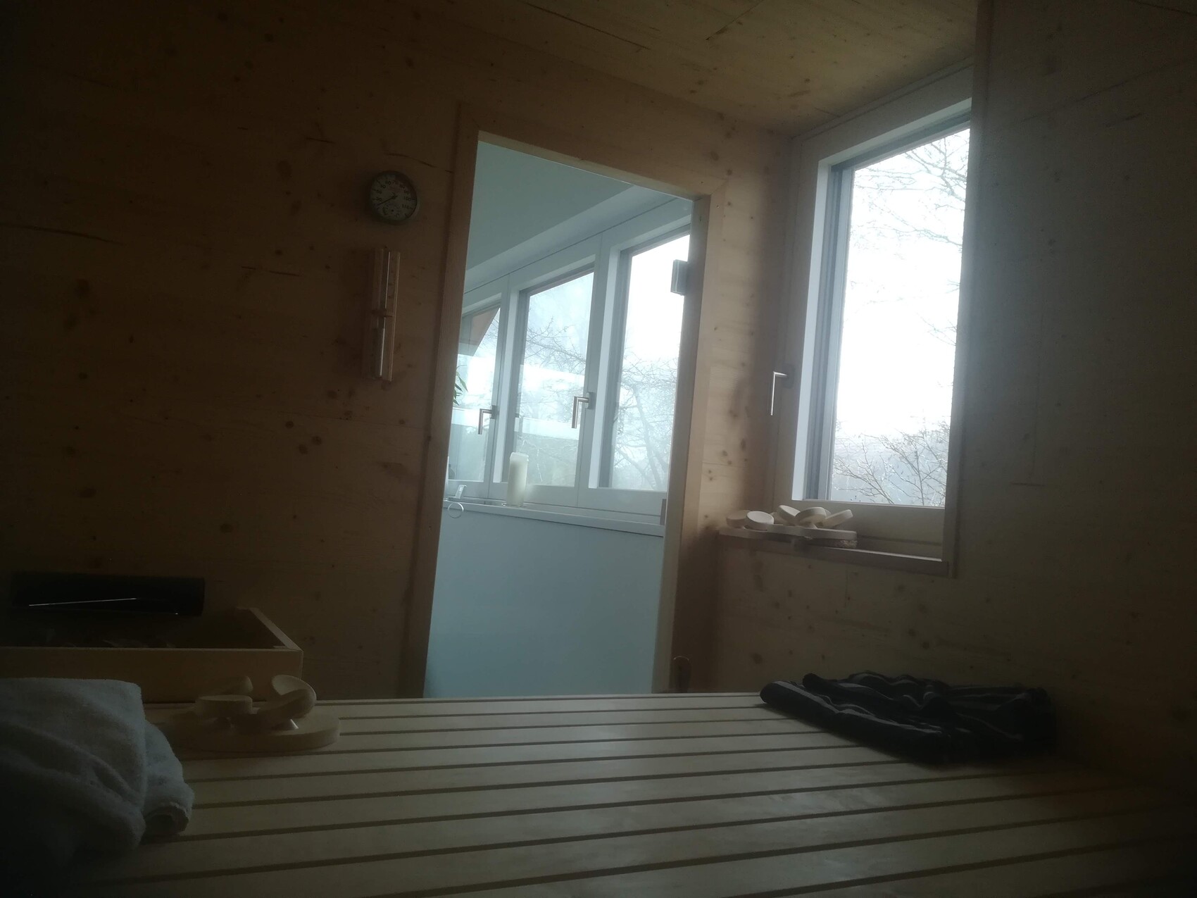 Holzsauna-Innenraum mit Bänken; Fenster zeigt verschneite Winterlandschaft.
