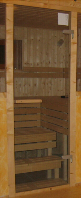 Innenraum einer Sauna aus Holz mit mehrstufigen Bänken und Tür am Eingang