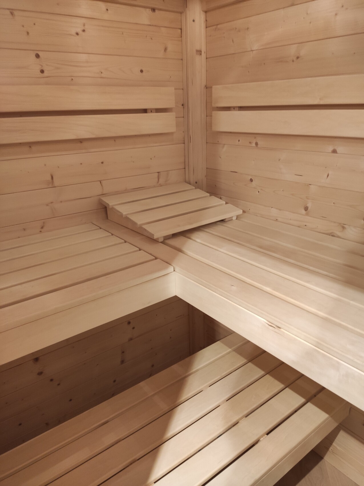 Heller Saunaraum aus Holz mit mehrstufigen Bänken in einer Ecke