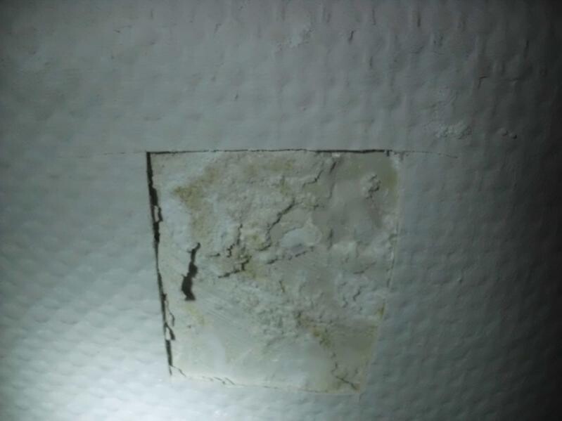 Abgenutzte Wand mit Putzrissen und beschädigter Putzschicht.