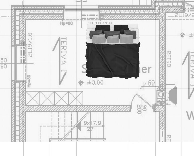 Bett mit schwarzem Bezug und grauen Kopfkissen vor Bauplan-Hintergrund.