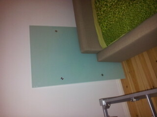 Schlafzimmer mit grauem Bettrahmen, gruene Bettdecke und hellblaue tuer.