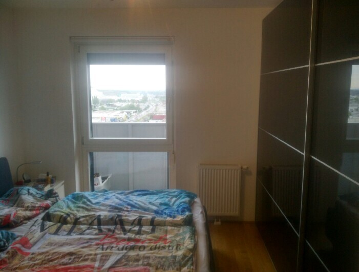 Schlafzimmer mit Bett, großem Fenster und Blick nach außen, Kleiderschrank sichtbar.