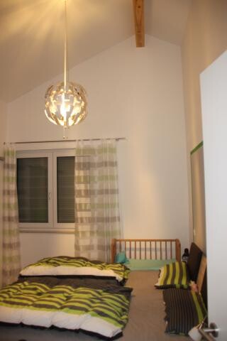 Schlafzimmer mit Bett, Fenster, Vorhänge und Pendelleuchte