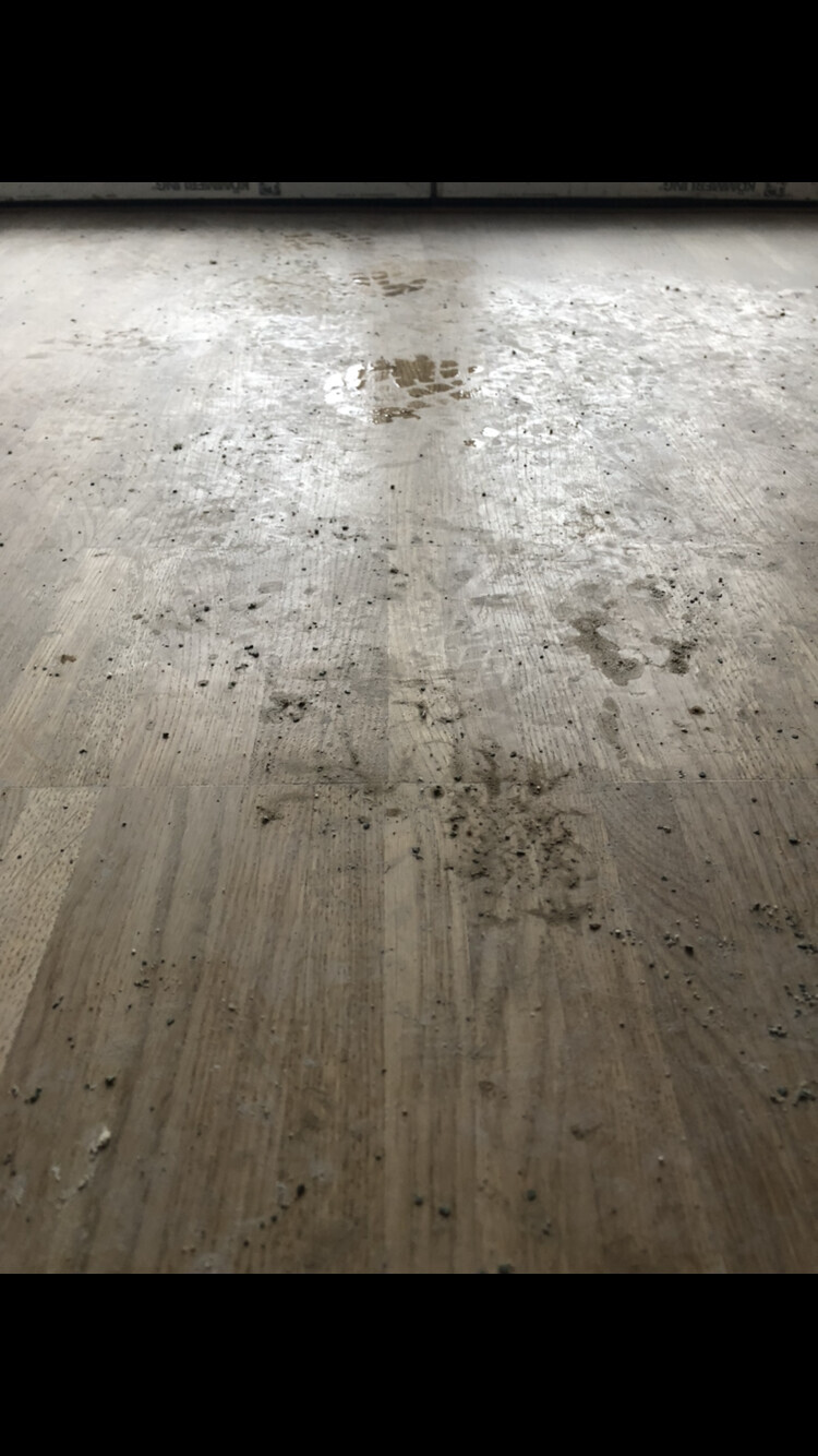 Holzboden im Innenraum mit nassen Flecken, Staub und Schmutz