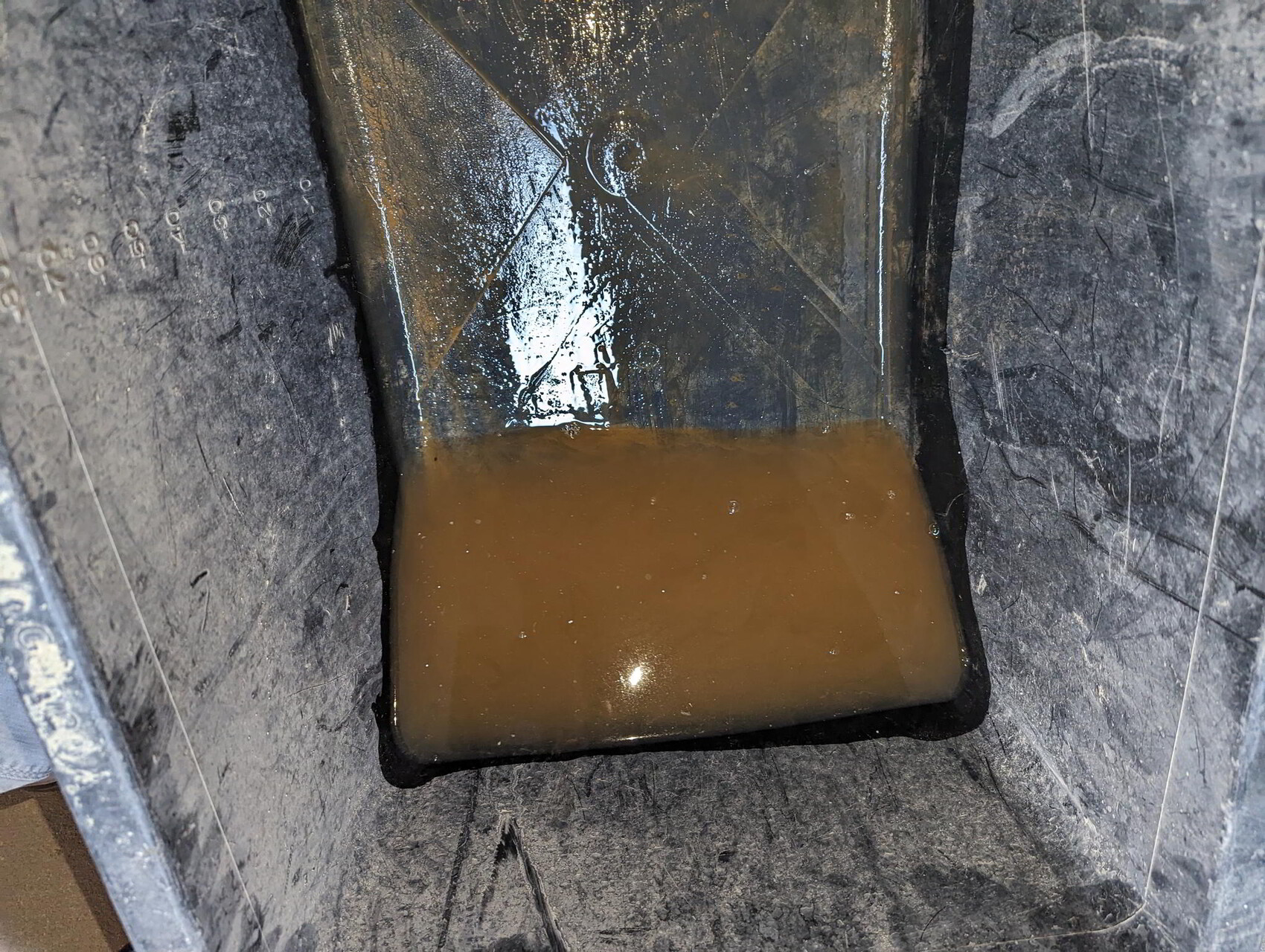 Metallwanne mit braunem, trübem Wasser und Schlamm am Boden.