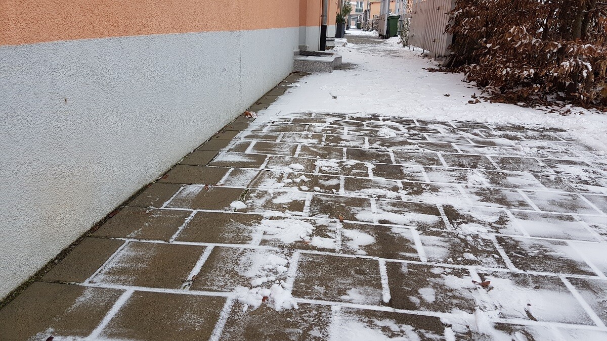 Winterlicher Pflasterweg vor Wohnhaus mit Schnee