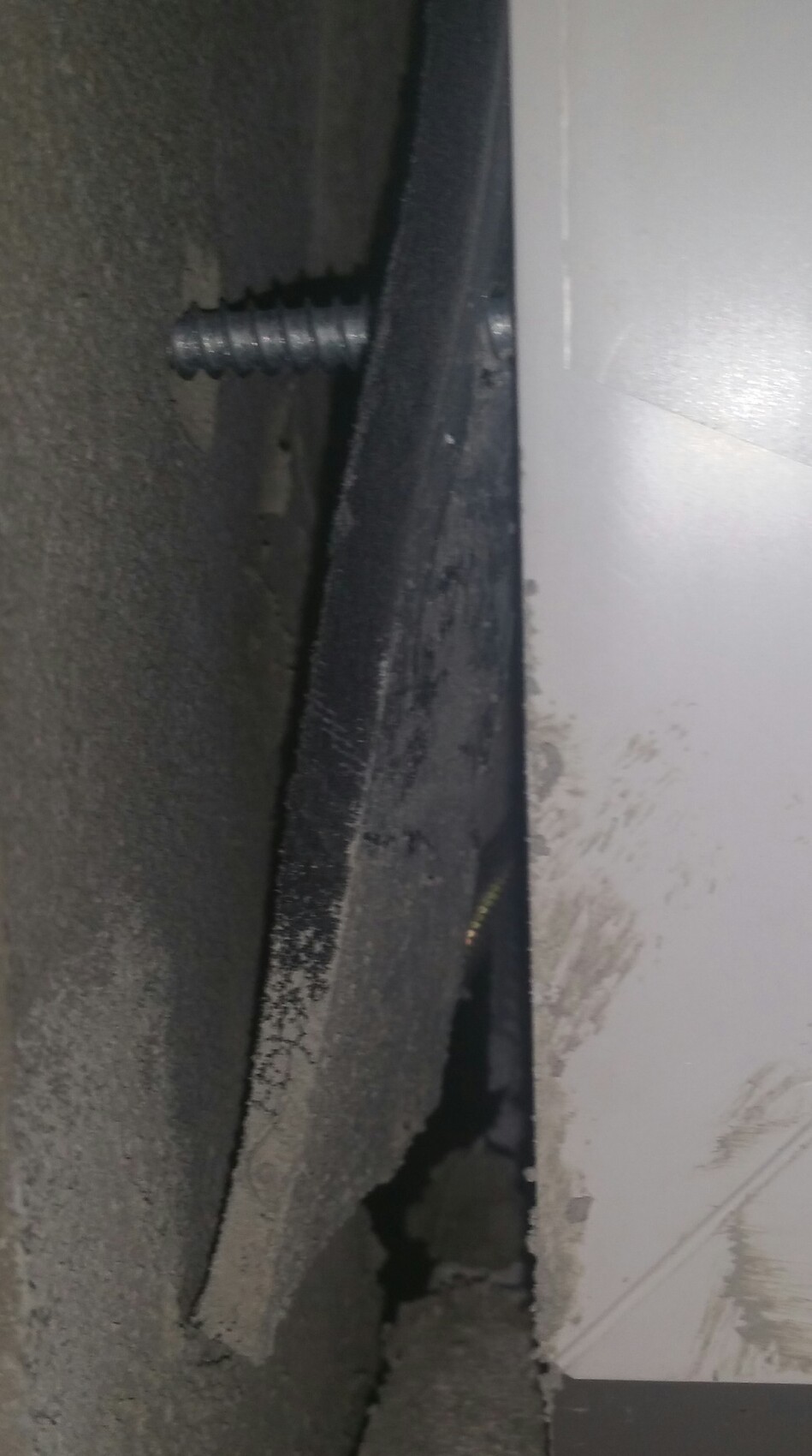 Schraubanker in Betonwand mit Putzfragmenten am Baustellendetail