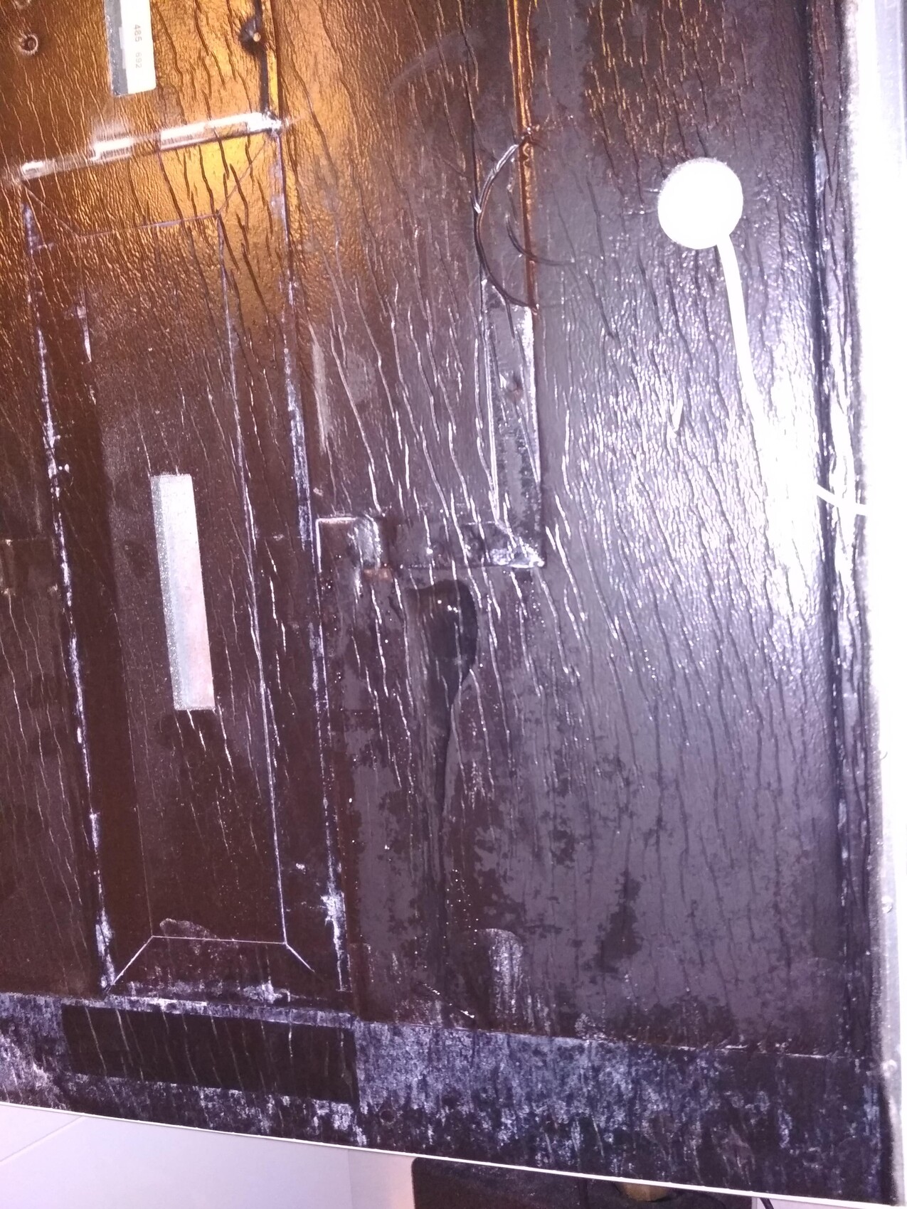 Schwarz lackierte Holztuer mit Kratzern und Kleinteilen an der Oberflaeche im Bauzustand