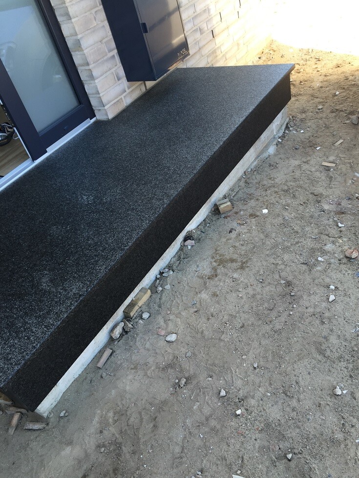 Schwarze Granitbank als Außenbank vor der Hausfassade am Eingang
