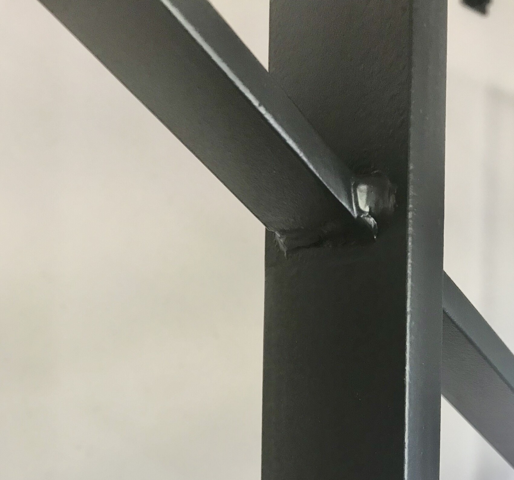 Nahaufnahme einer schwarzen Metallkonstruktion mit diagonalem Querträger und Schweißnaht.