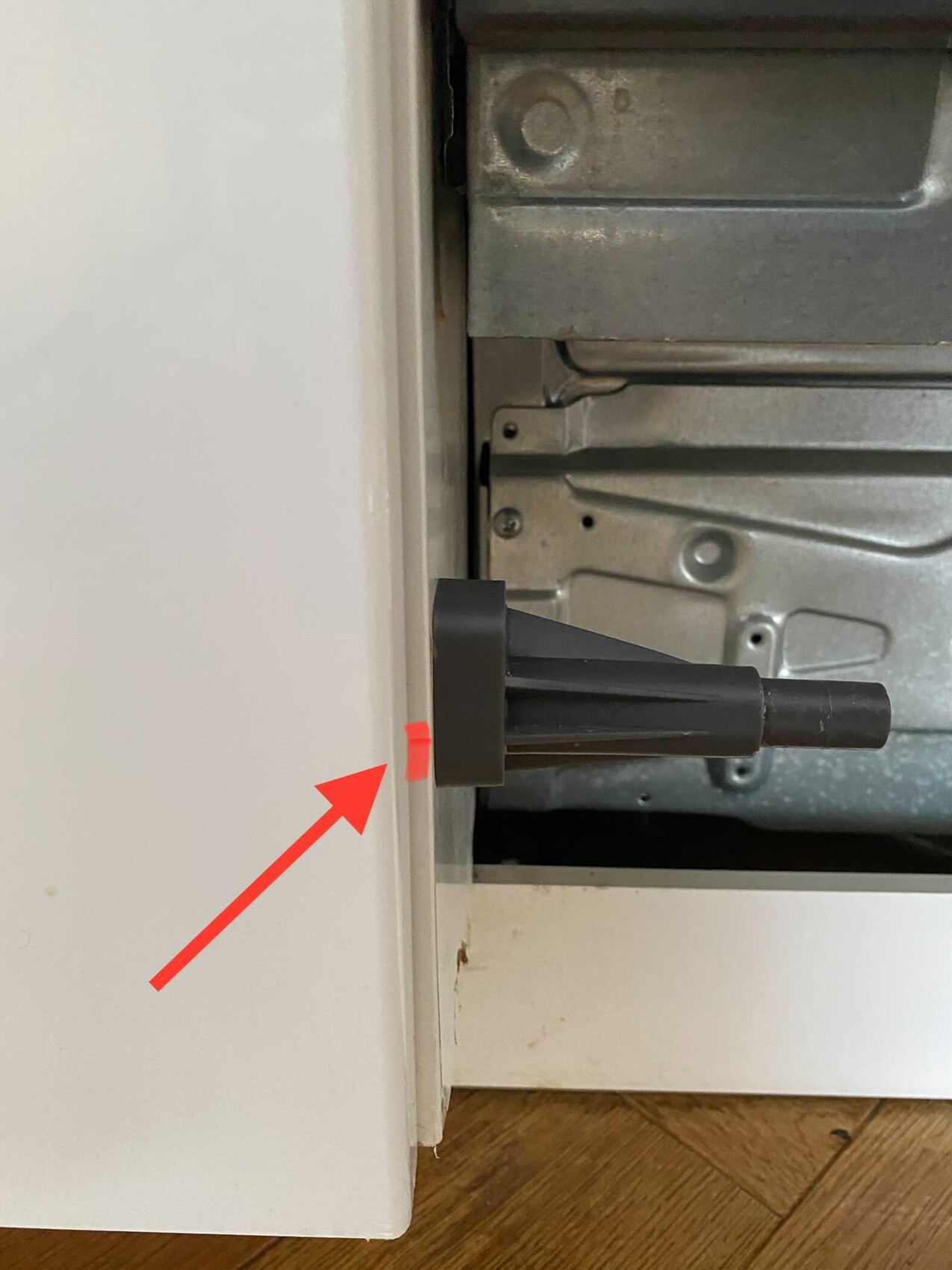 Schwarzes Kunststoffteil ragt durch eine Metallinnenwand; roter Klebestreifen markiert Rand.