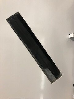 Langes schwarzes Fensterrahmenprofil liegt diagonal auf hellem Untergrund.