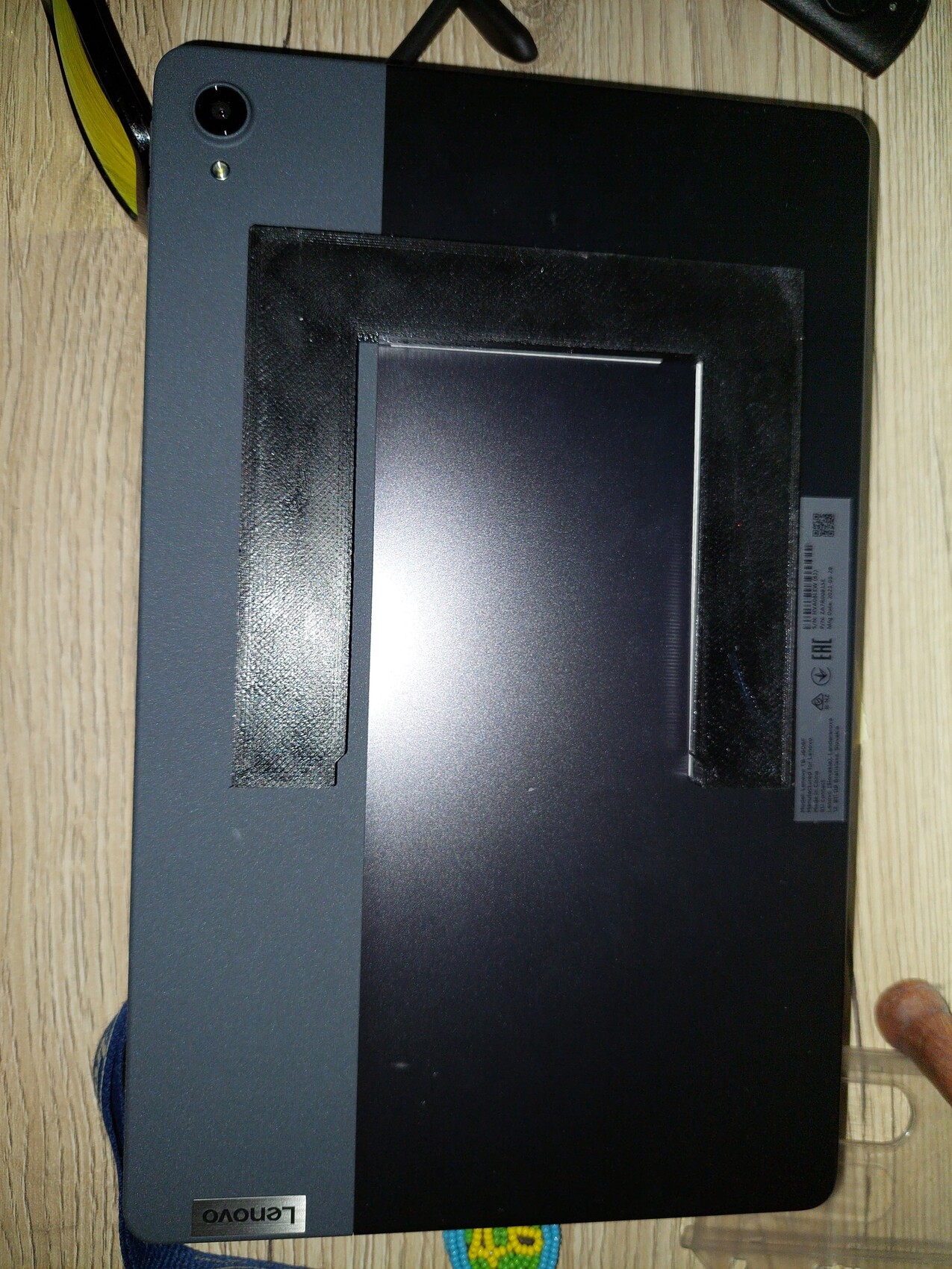 Geschlossener Lenovo-Laptop auf einer Holzoberfläche, von oben fotografiert, Kabel seitlich.