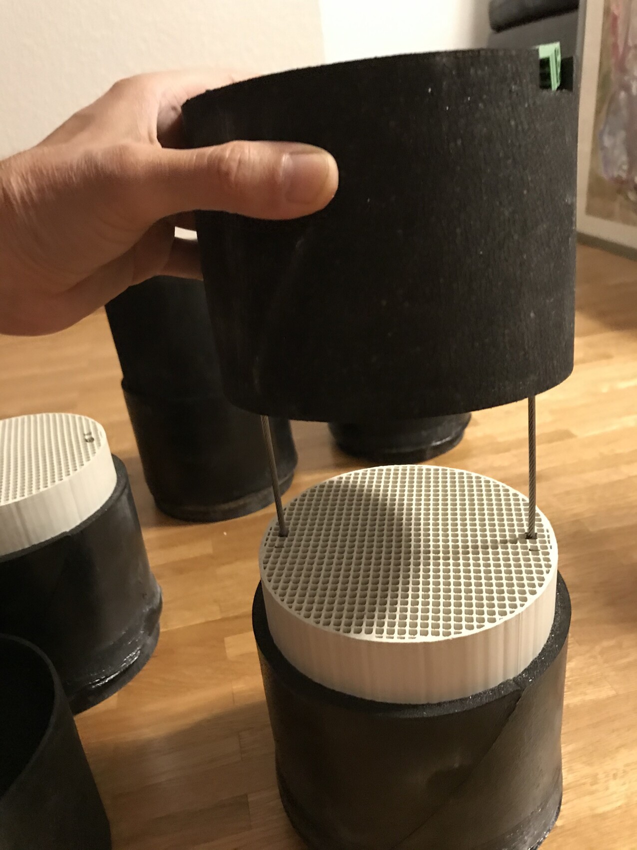 Hand platziert schwarzes Filterschwamm-Top über weißem perforierten Filterring eines DIY-Luftfilters.