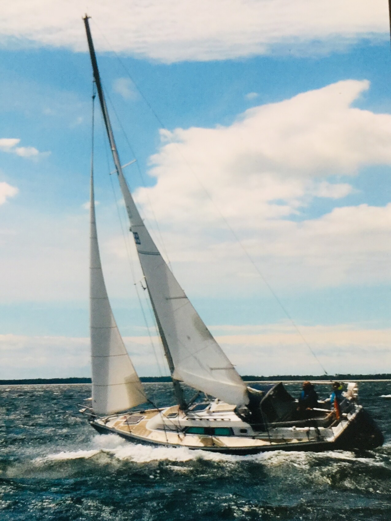 Segeljacht mit zwei Segeln, Personen an Deck auf offener See.