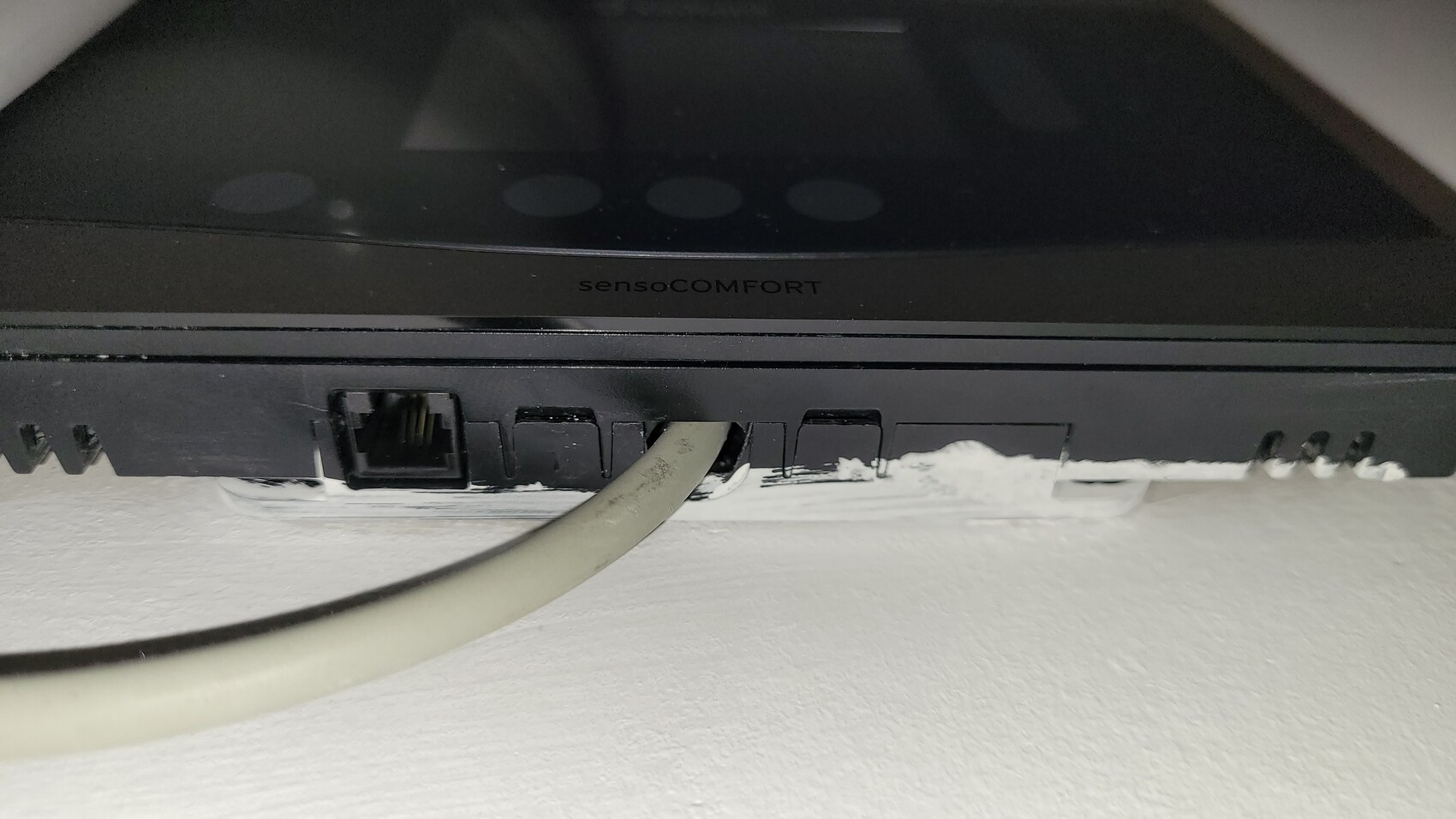 Nahaufnahme eines schwarzen sensocomfort Haustechnikgeräts mit Ethernet-Port an der Wand