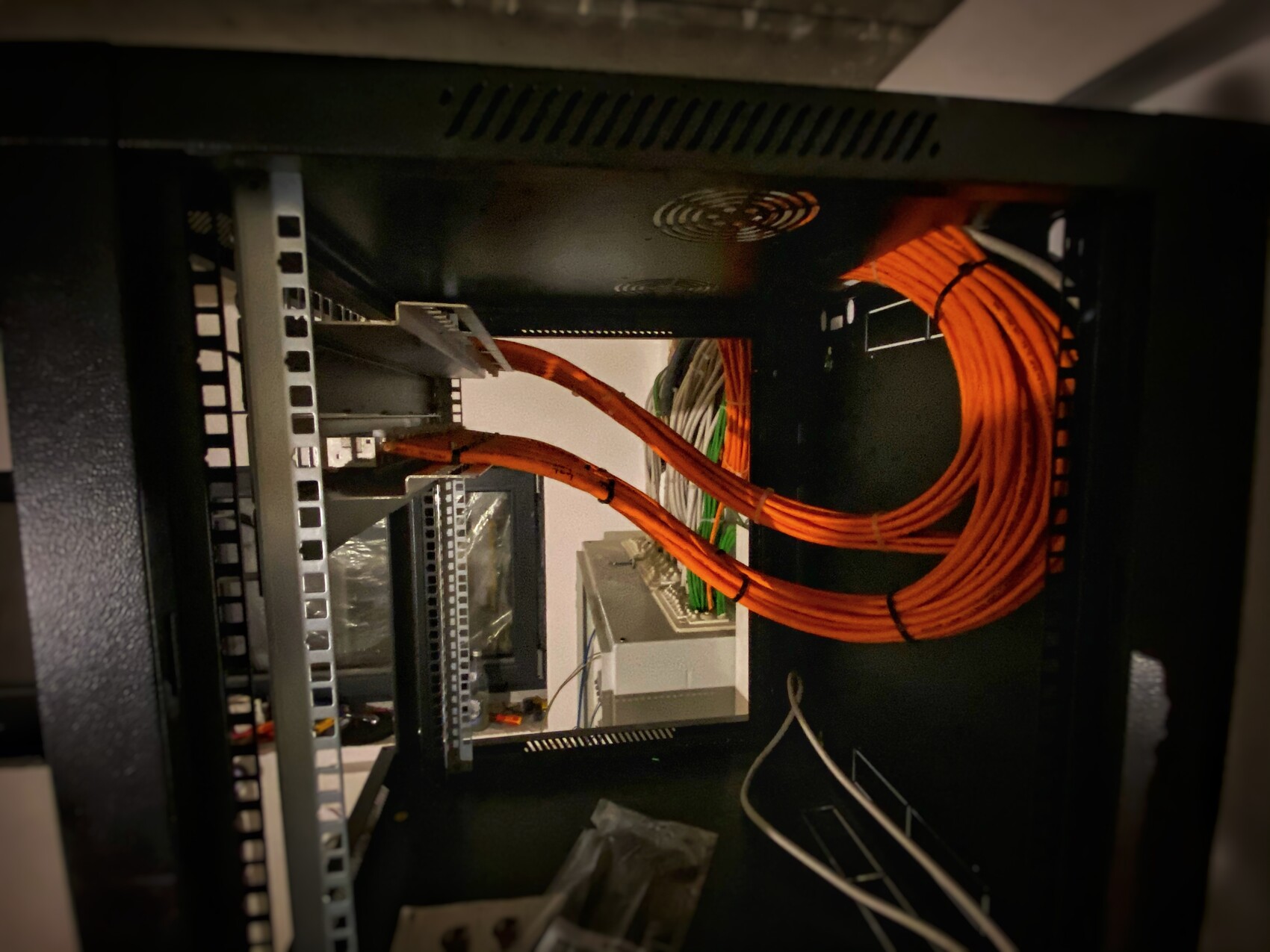 Serverschrank mit orangefarbenen Kabelbündeln und Patchpanels im Inneren.