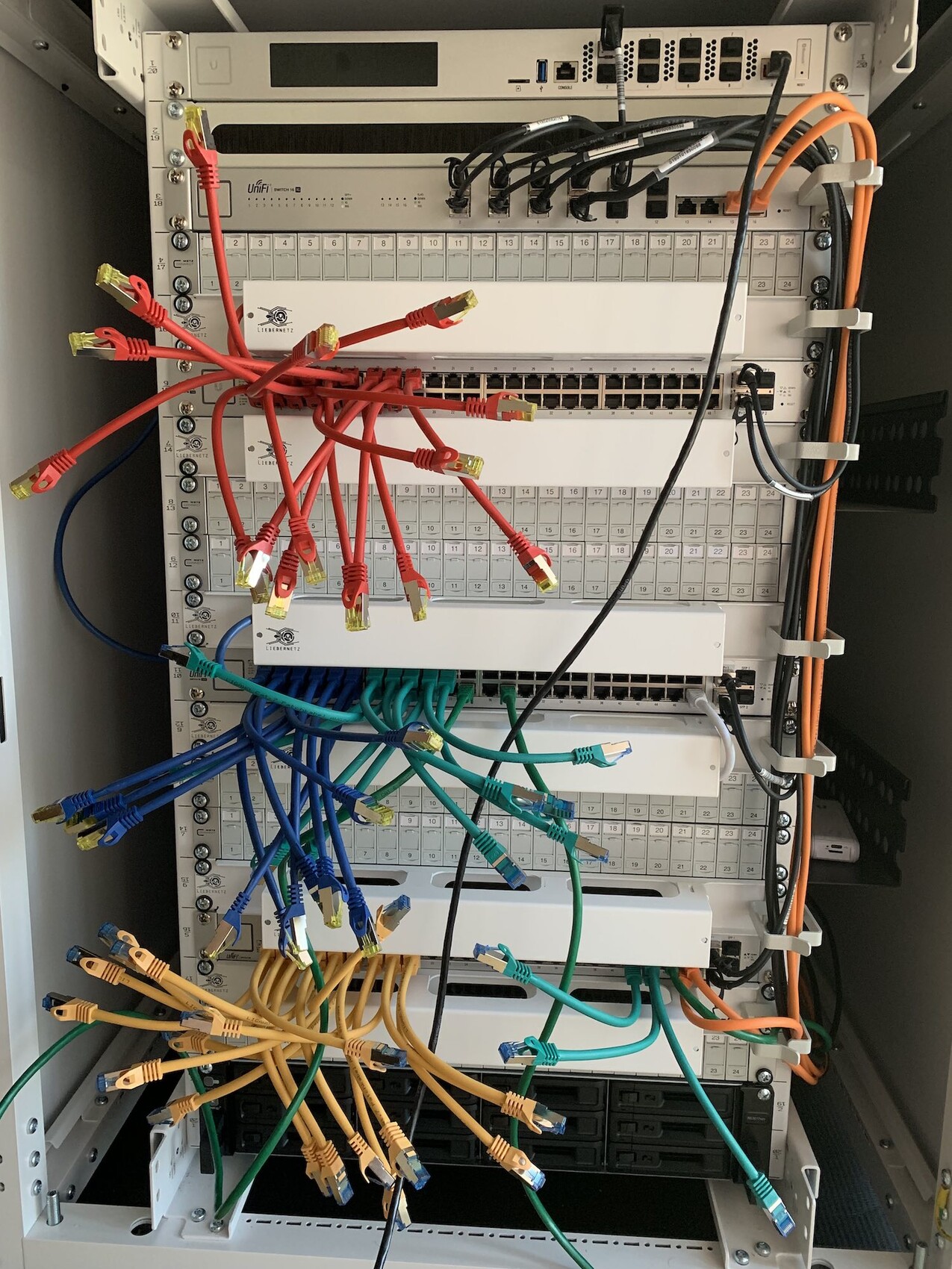 Serverrack mit bunten Netzwerkkabeln, Patchpanel und Switches im Rechenzentrum