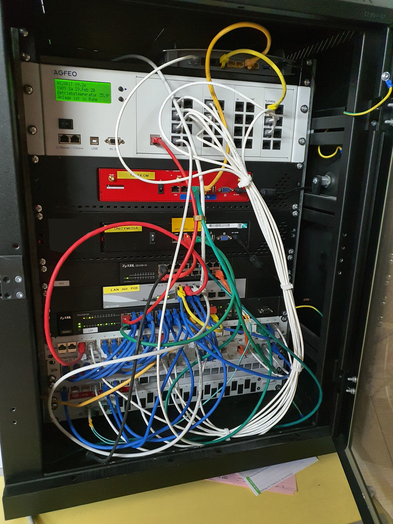 Netzwerkrack mit Servern, Switches und bunten Kabeln; Kabelsalat im Frontbereich.