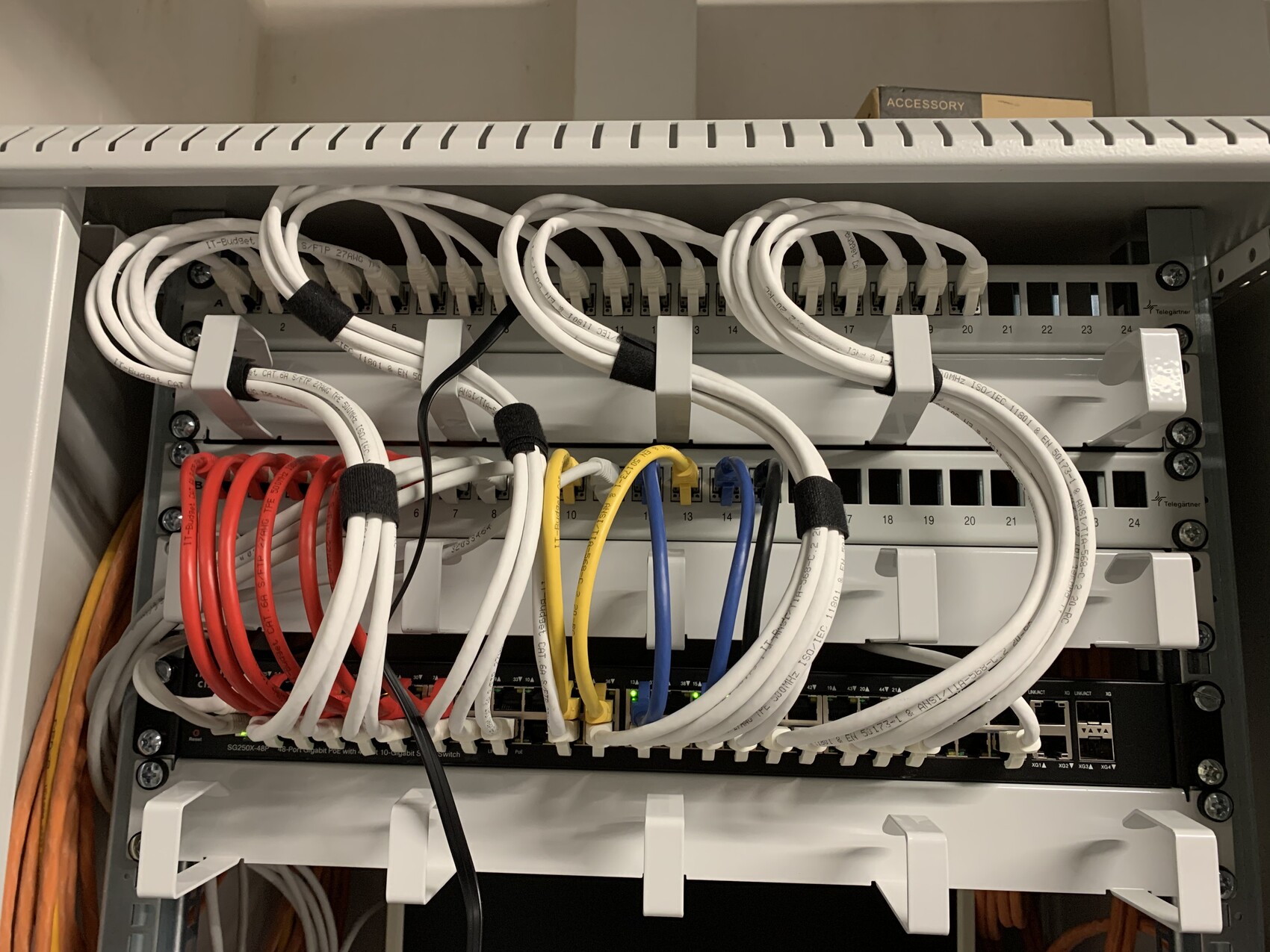 Serverschrank mit Patchfeld und bunten Kabelbünden (weiß, rot, blau, gelb).