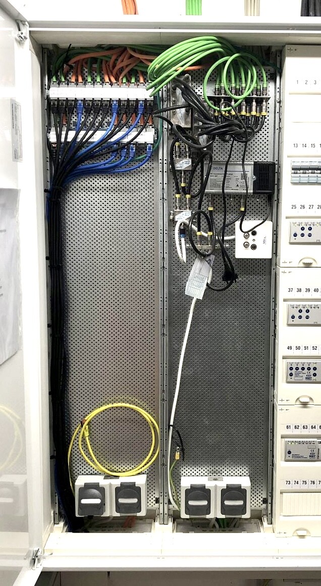 Elektroverteilerschrank mit vielen farbigen Kabeln und Steckdosenleisten.
