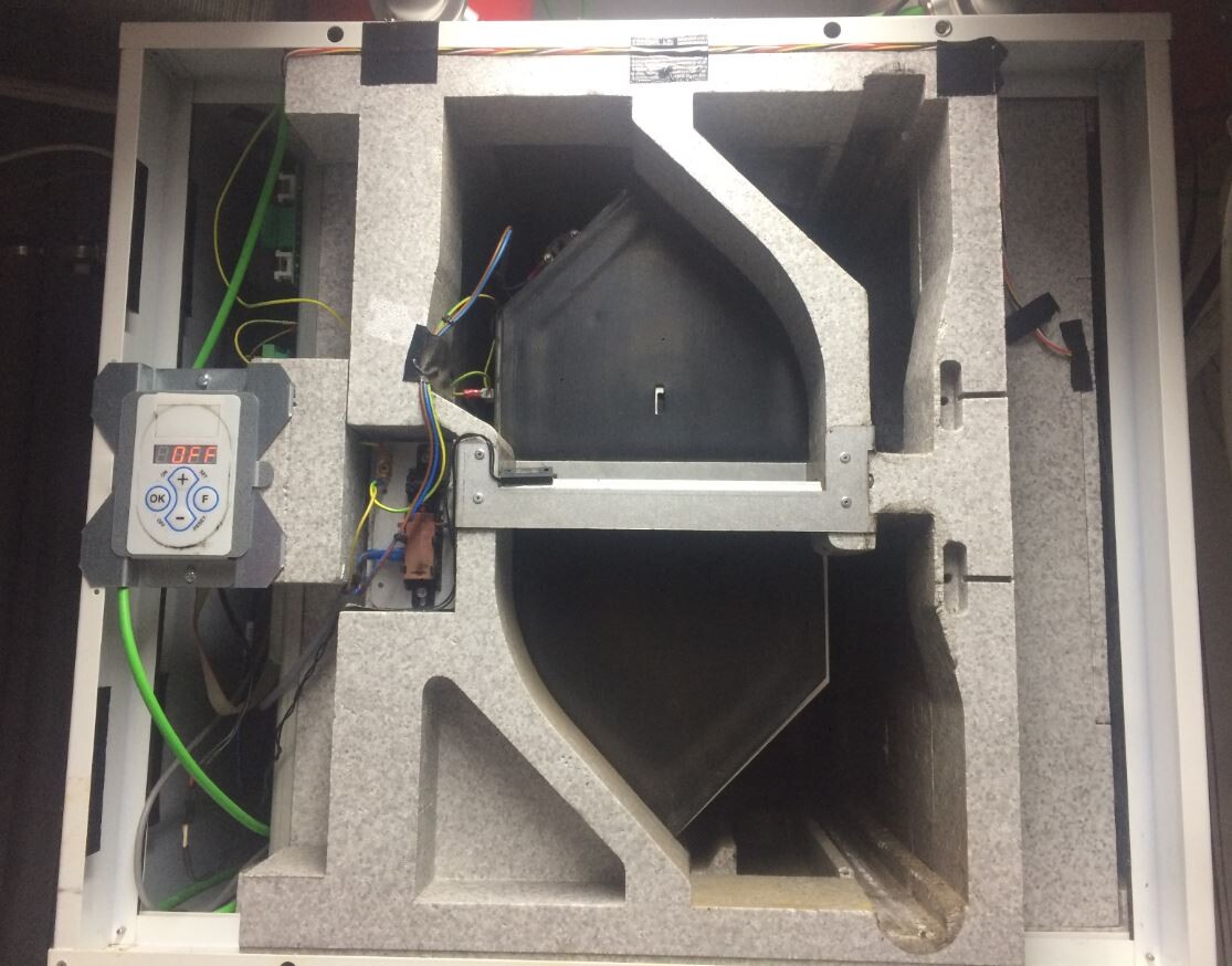Innenansicht eines Lüftungs- oder Ventilatorenkastens mit Steuereinheit, Kabeln und Dämmung.