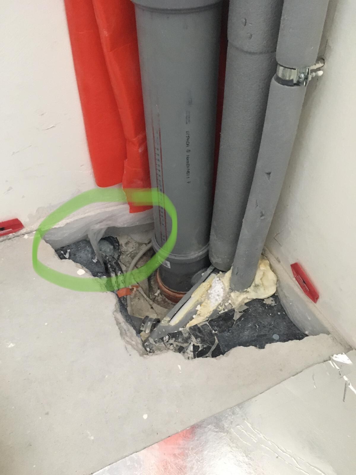 Offene Rohrleitungen in Rot und Grau, Bodenaufbruch, freiliegte Kabel und Dämmmaterial.