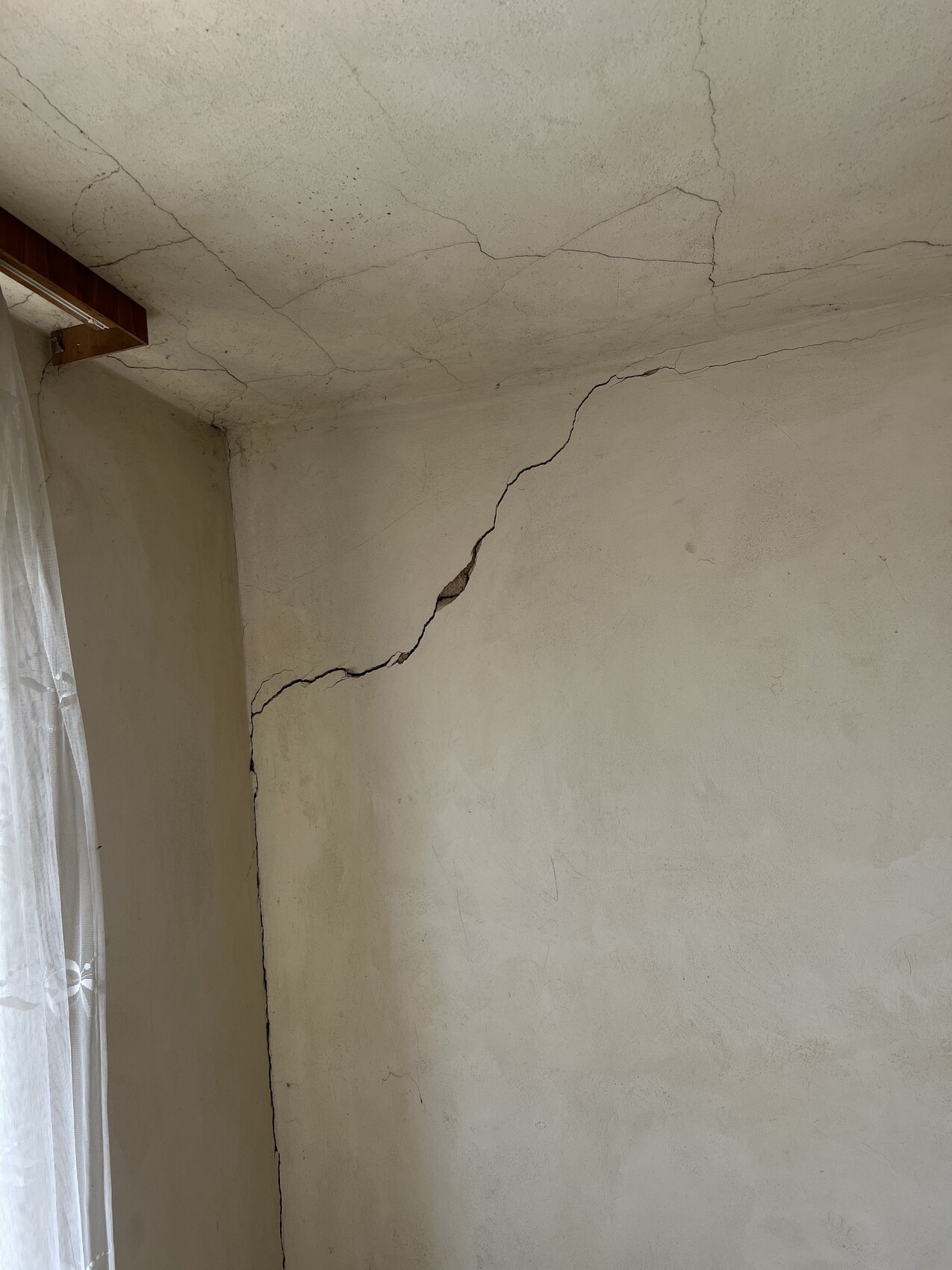 Risse in Wand und Decke eines Innenraums, Hinweis auf Baumängel