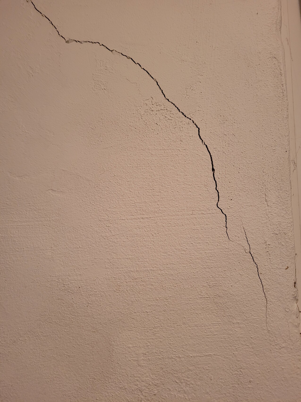 Große Putzwand mit einer dunklen Risslinie von oben links nach unten rechts.