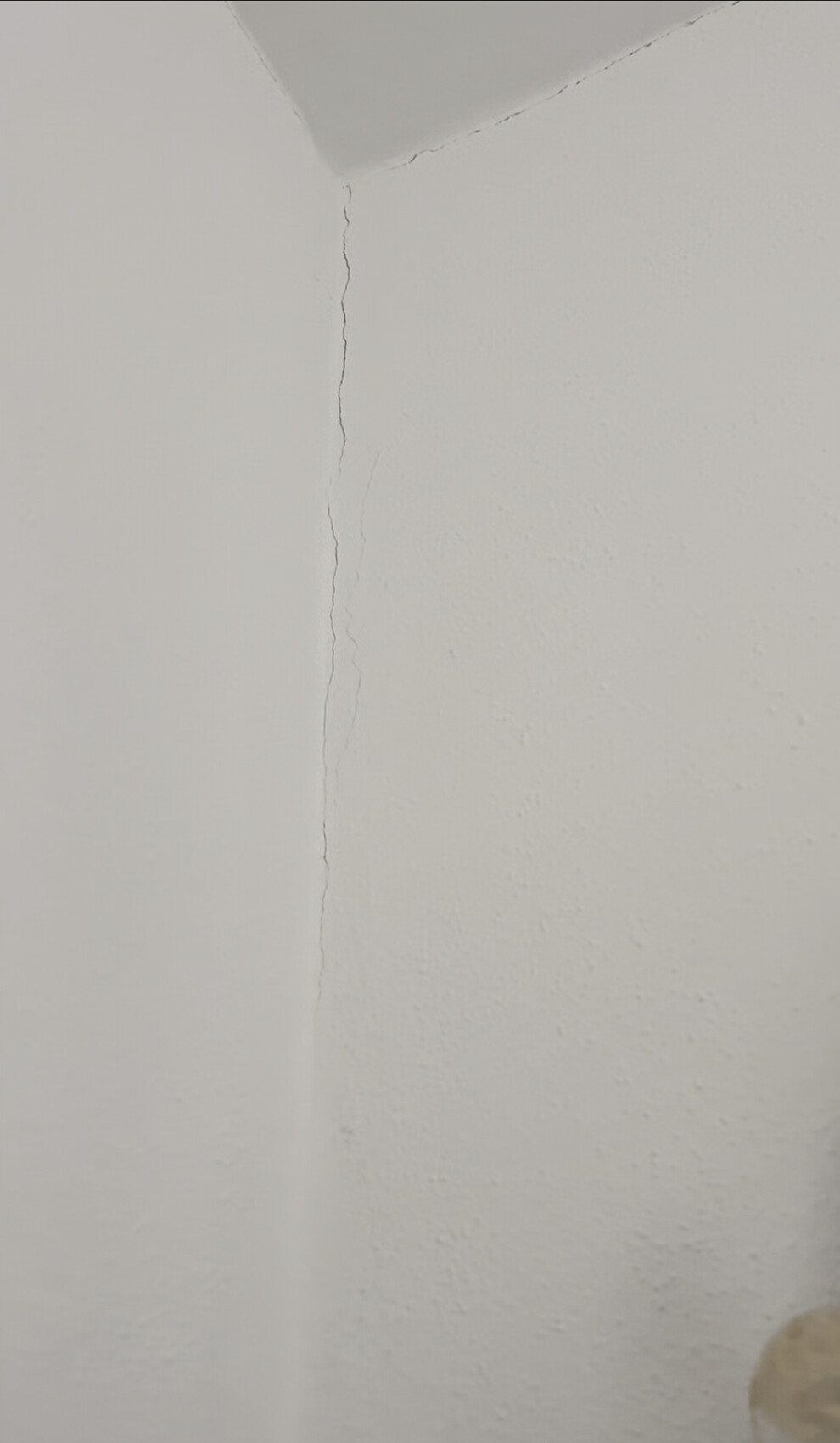 Weißes Innenraum-Eck mit deutlicher vertikaler Risslinie in der Wand.