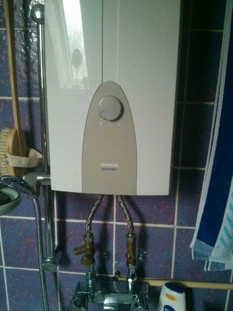 Kompakter Siemens-Boiler im Badezimmer, Rohre und Fliesen sichtbar.