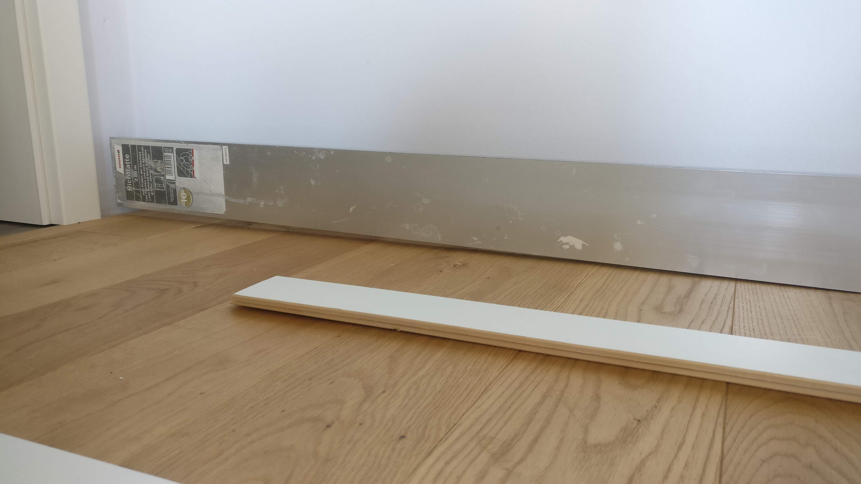 silberne-sockelheizung-an-wand-montiert-holzfussboden.jpg